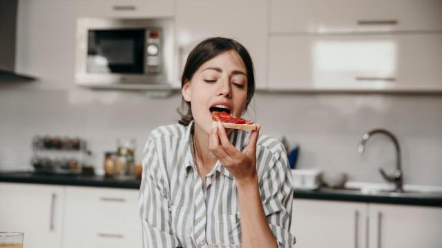 Una mujer comiendo una tostada.