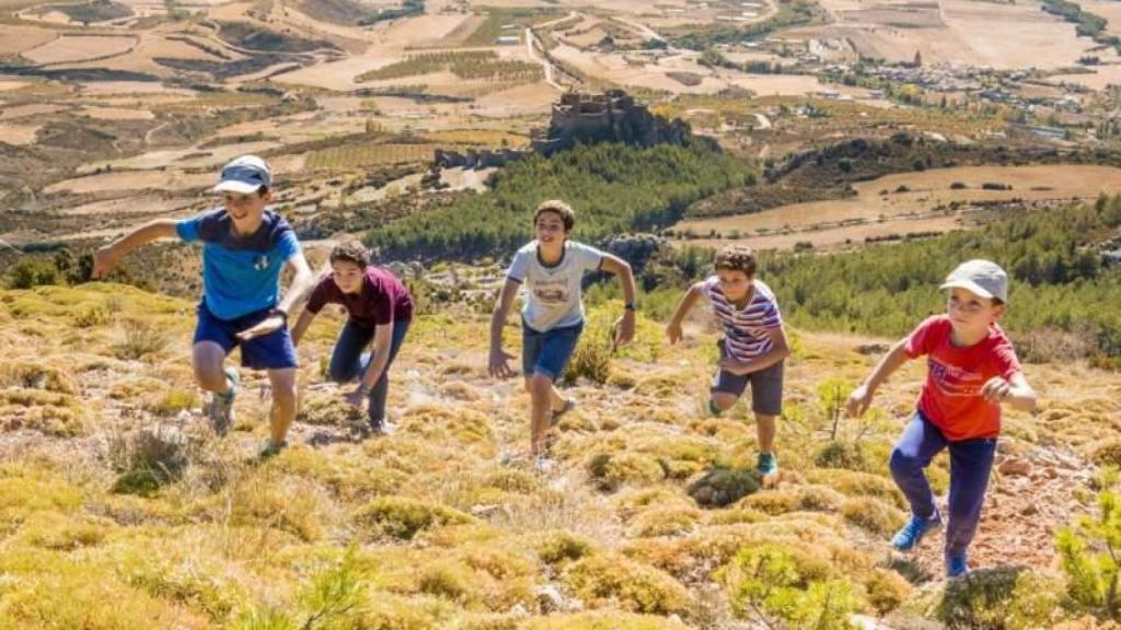 Niños corriendo en la ladera con el castillo de Loarre detrás.