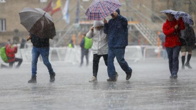 Varias personas se cubren de la intensa lluvia.