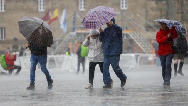 Varias personas se cubren de la intensa lluvia.