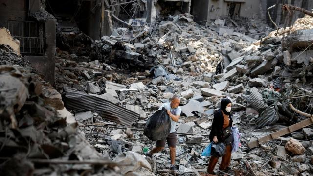 Un hombre y una mujer pasean entre los escombros provocados por un bombardeo israelí en Beirut el  11 de octubre de 2024