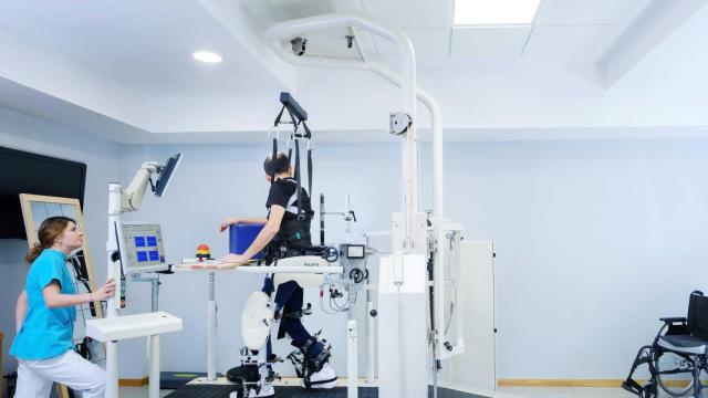 Fisioterapeuta del equipo de neurorrehabilitación del Hospital Quirónsalud Miguel Domínguez supervisa la marcha robotizada de un paciente.