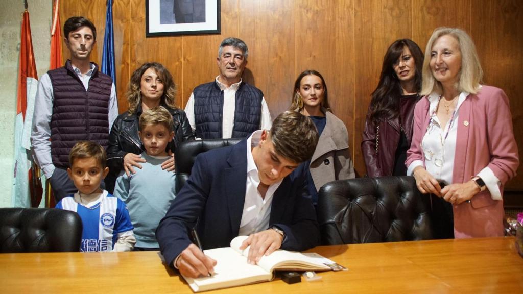 Pica firma en el libro de honor en presencia de su familia detrás y la alcaldesa albense