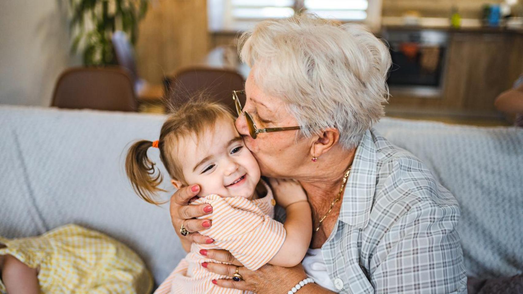 Abuela besando en la mejilla a su nieta.