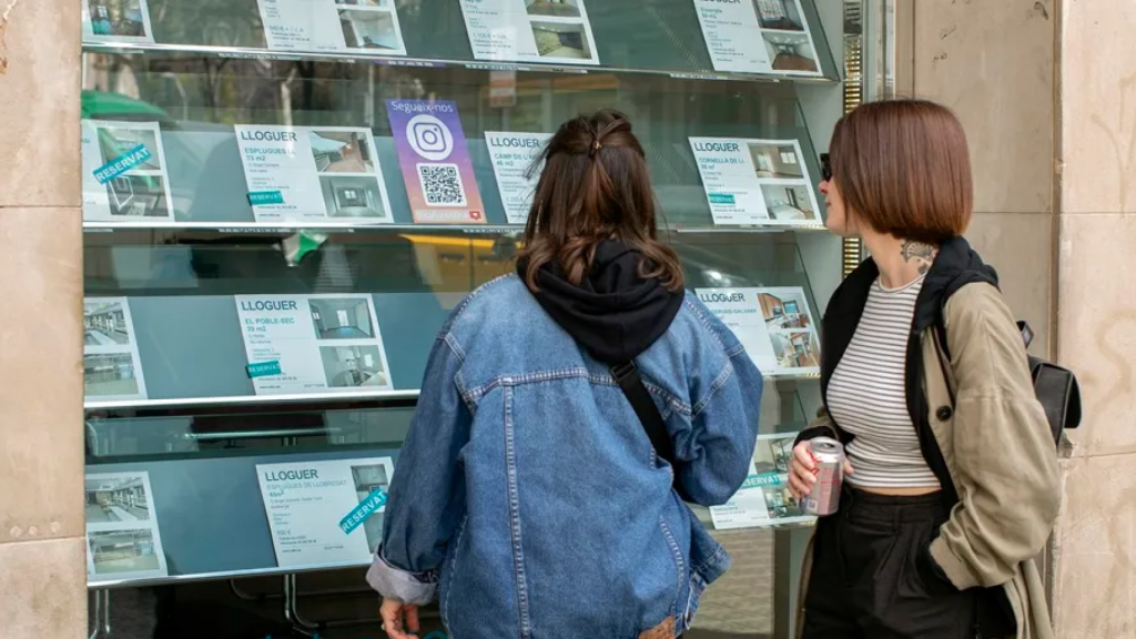 Dos chicas miran pisos en alquiler en una inmobiliaria.