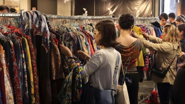 Varias personas comprando ropa de segunda mano.