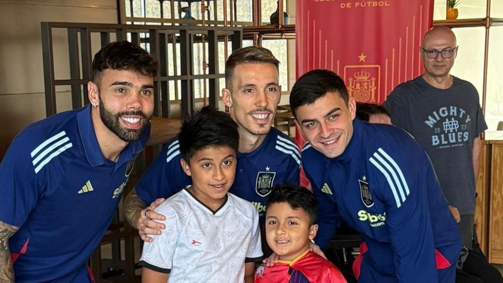 Los internacionales por España, David Raya, Grimaldo y Pedri, posando con un sonriente Luciano, de 7 años, vestido con su capa de 'Super Lucky', junto a su hermano mayor, Juan, de 9 años.