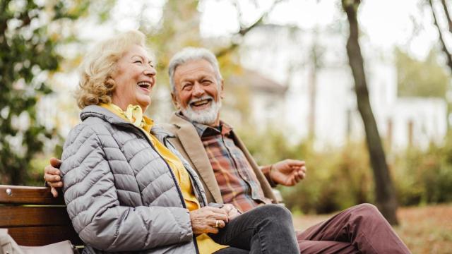 Una pareja de ancianos sentados en un banco y felices.