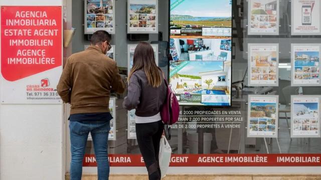 Imagen de archivo de una pareja observando las propiedades en venta anunciadas en el escaparate de una agencia inmobiliaria. EFE/David Arquimbau Sintes