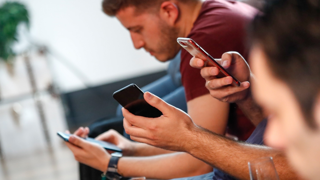 Varios jóvenes mirando su teléfono móvil.