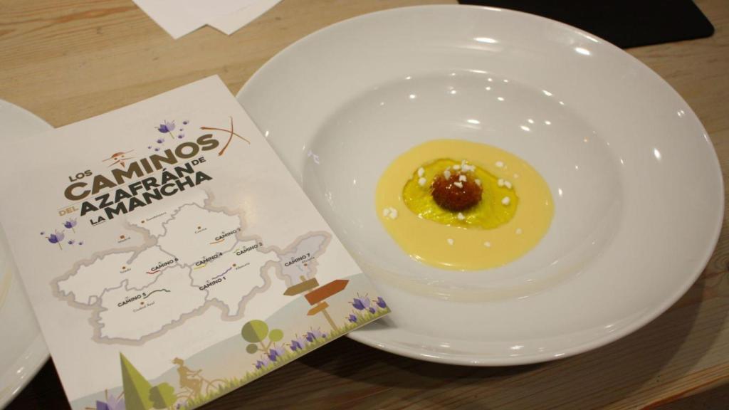 Un folleto de 'Los caminos del azafrán de la Mancha' junto a un plato elaborado con dicho producto.