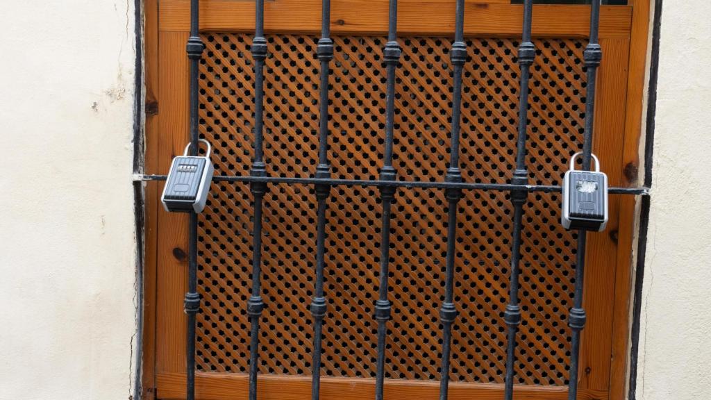 Candados de pisos turísticos en una ventana de Sevilla.