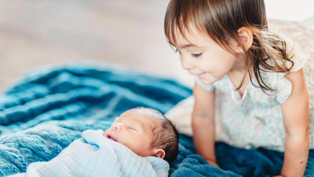 Niña pequeña junto a su hermano recién nacido.