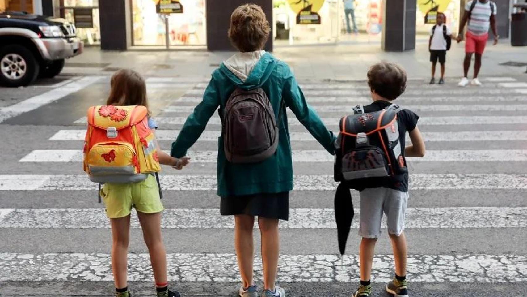 Una madre lleva a sus dos hijos al colegio durante el primer día de curso escolar en Valencia.