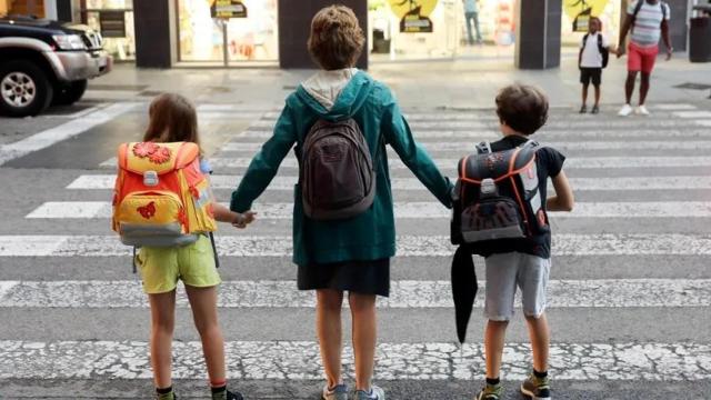 Una madre lleva a sus dos hijos al colegio durante el primer día de curso escolar en Valencia.