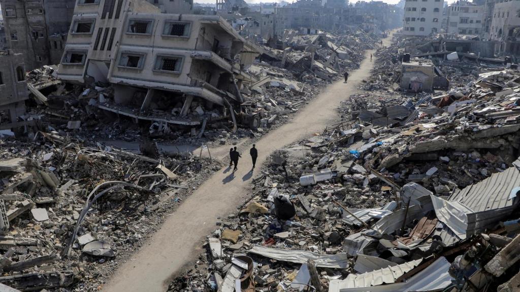 Palestinos caminan frente a casas destruidas en el campo de refugiados de Jabalia.