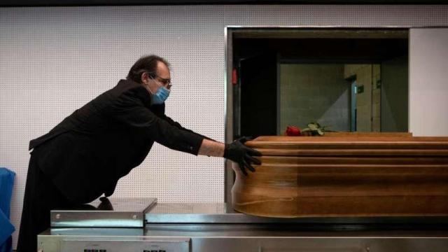 Un trabajador de una funeraria introduce un ataúd en un horno crematorio.