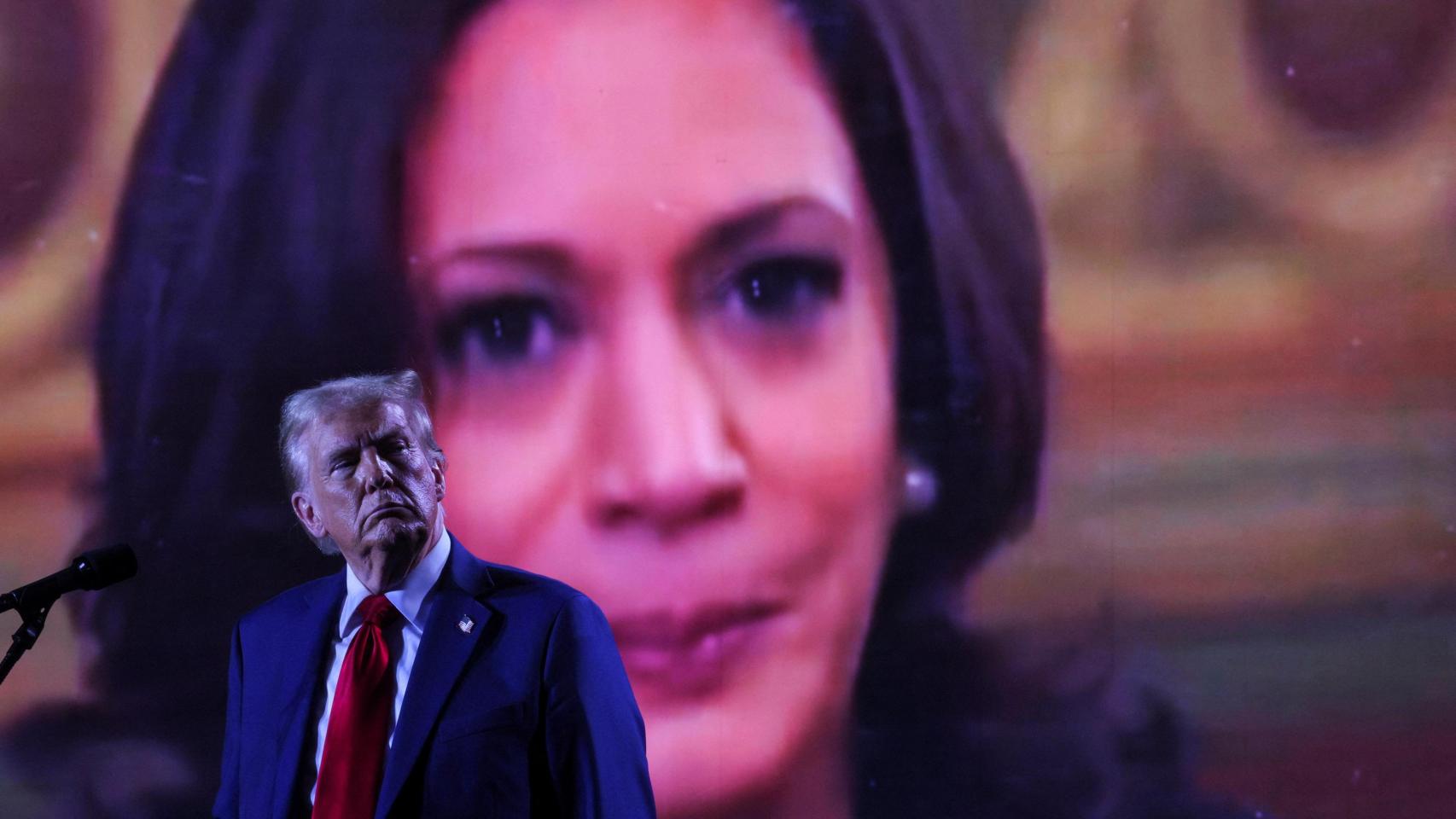 El expresidente estadounidense Donald Trump, delante del rostro de la candidata presidencial demócrata Kamala Harris en una pantalla, durante un mitin en Huntington Place en Detroit.