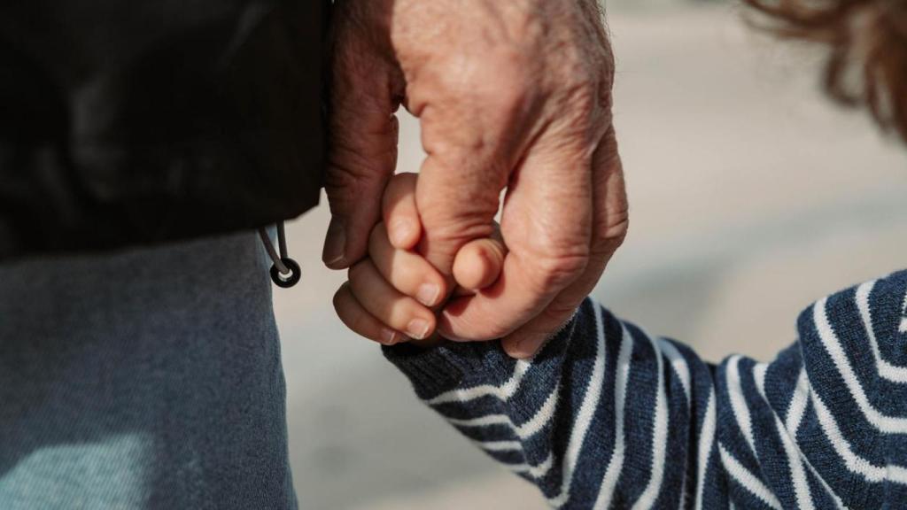 Abuelo sosteniendo a su nieto de la mano.