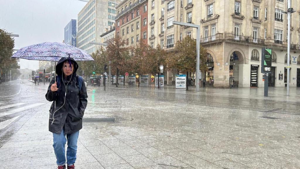 Una mujer con un paraguas se protege de la lluvia en la plaza de España de Zaragoza.