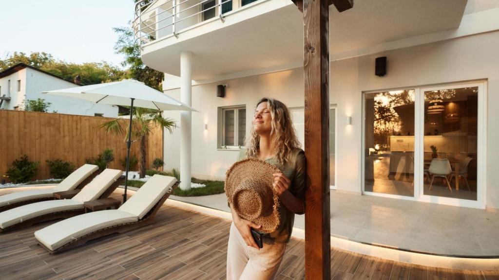 Una mujer sonriente disfrutando en el exterior de su casa.