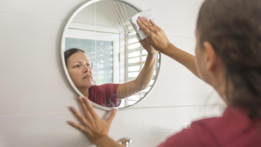 Una mujer limpiando un espejo.