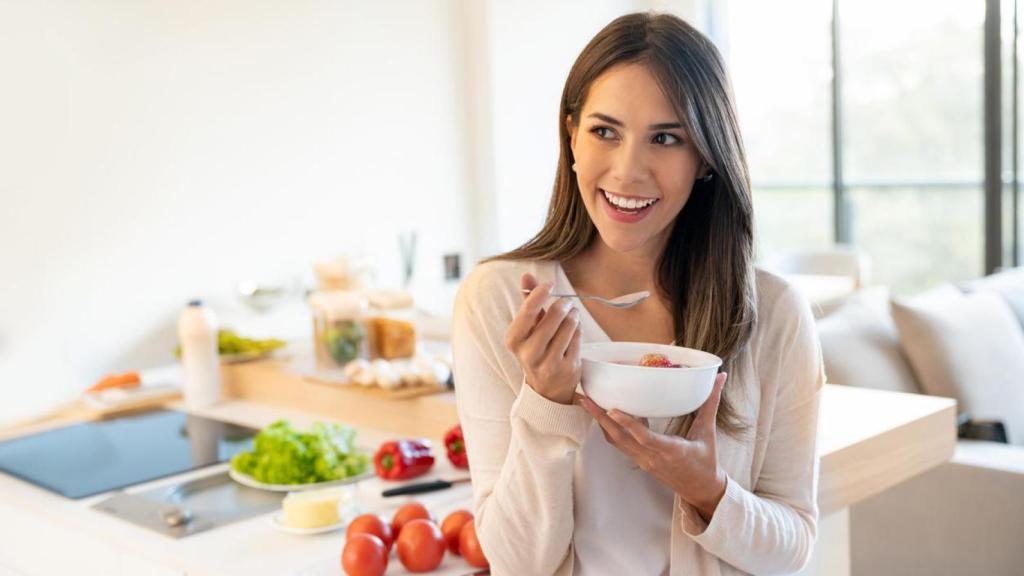 Mujer desayunando en la cocina de su casa.