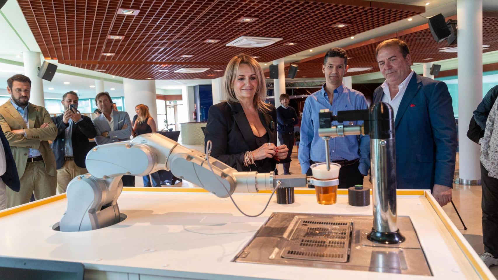 La consellera Nuria Montes, el hotelero Fede Fuster y el CEO de Bumerania Robotics, Isidro Fernández junto al brazo robotizado cervecero.,