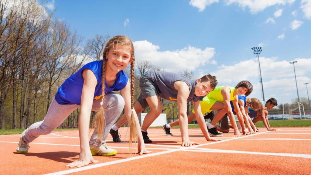 Grupo de corredores adolescentes alineados listos para correr.