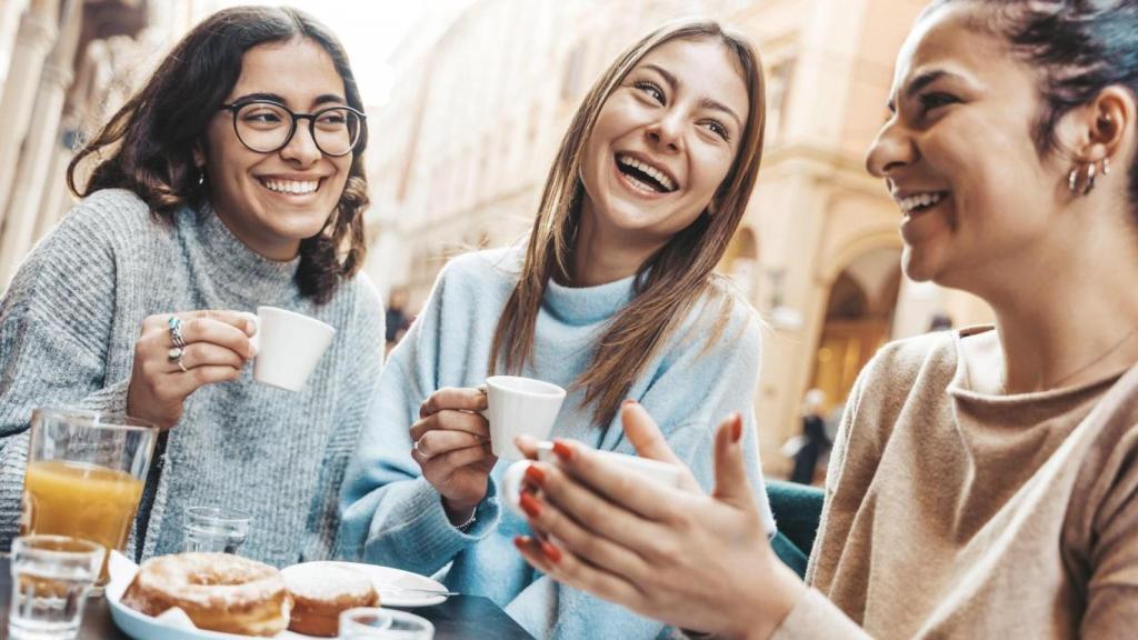 Un grupo de mujeres disfrutando de un desayuno con café y dulces.