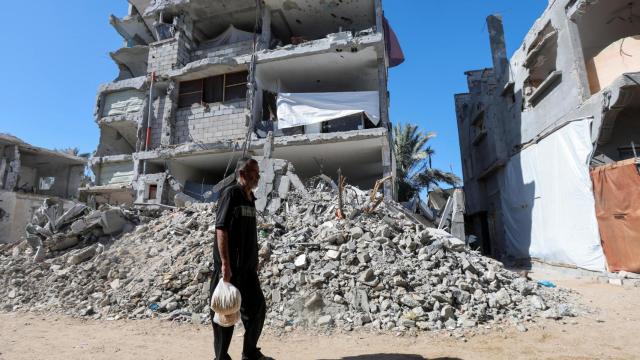 Un hombre palestino camina frente a los escombros resultantes de la guerra en la Franja de Gaza