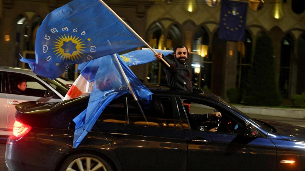 Un simpatizante del partido Sueño Georgiano ondea la bandera del partido desde un automóvil después del anuncio de los resultados.