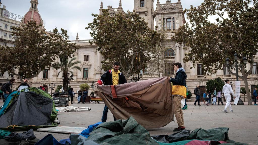 Participantes en la acampada por la vivienda instalada en la plaza del Ayuntamiento de Valencia recogen sus tiendas de campaña tras acordar desconvocarla. Efe / Biel Aliño