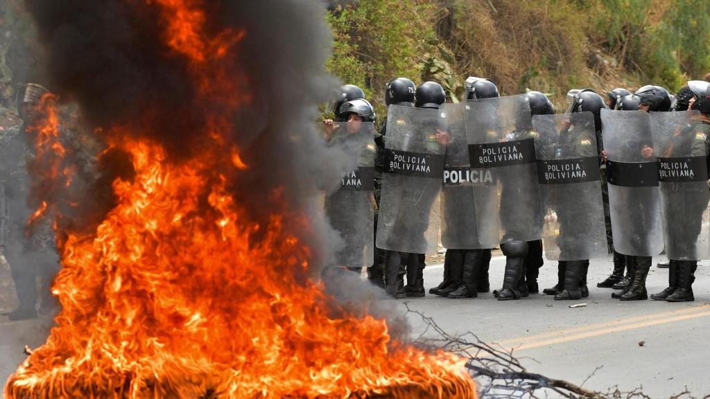 La policía interviene cerca de una barricada en llamas mientras intenta desmantelar un bloqueo establecido por partidarios de Evo Morales en protesta contra el Gobierno  de Luis Arce, en Parotani.