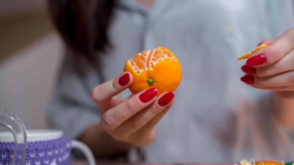 Mujer pelando mandarinas.