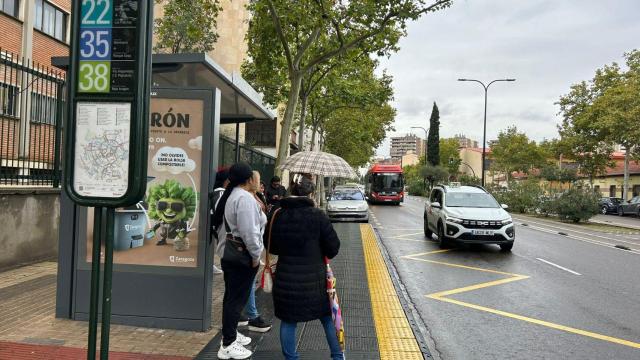 Usuarios esperando al autobús en una marquesina de Zaragoza, este lunes.