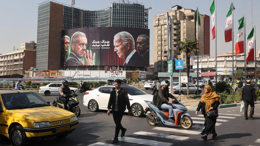 Los iraníes caminan junto a un cartel anti-estadounidense e israelí en Teherán, Irán.