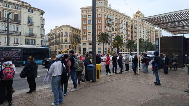 Personas esperando en una parada de autobús este lunes en Málaga.