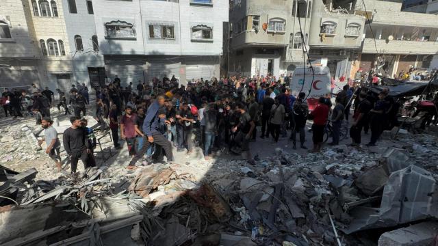 Palestinos inspeccionan los escombros de una escuela que alberga a personas desplazadas, en la ciudad de Gaza.