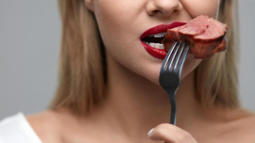 Mujer comiendo carne.