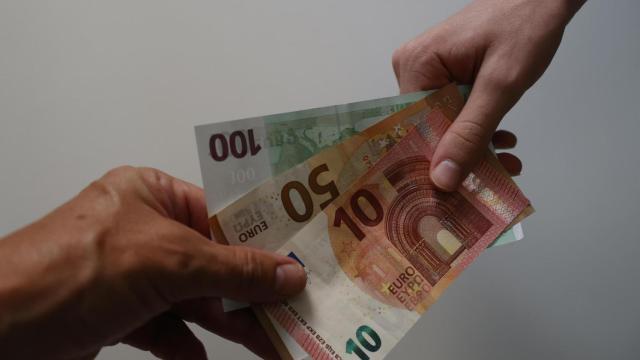 Dos personas pasándose billetes de euro.