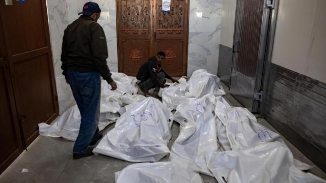 Dos palestinos junto a decenas de cadáveres tras los bombardeos de Israel sobre Gaza.