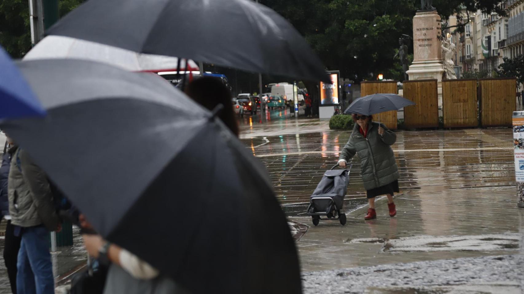 Una señora con paraguas bajo la lluvia.