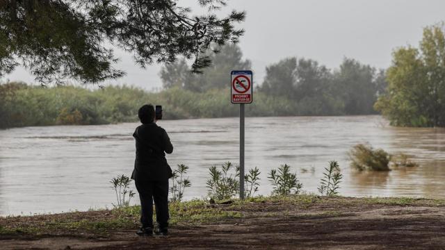 Una mujer toma imágenes del gran caudal del rió Júcar a su paso por Albalat