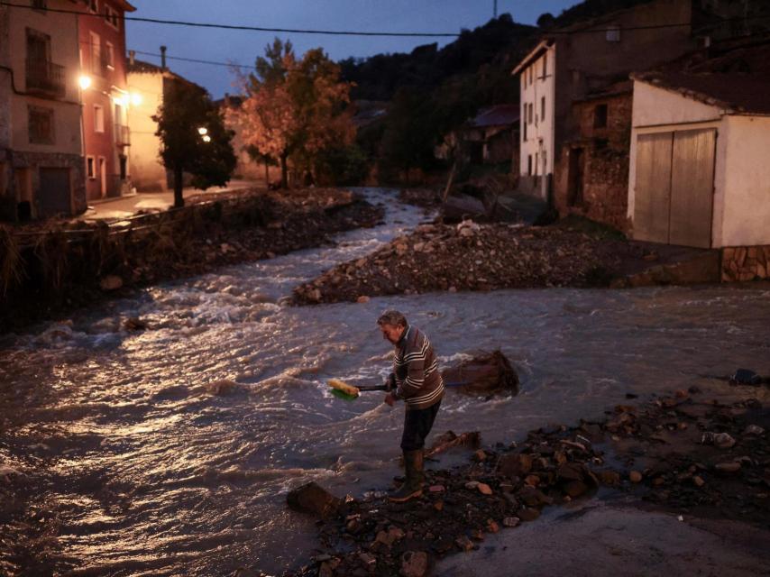 Miguel, de 69 años, lava sus escobas en el Río Seco después de limpiar su casa, en medio de las inundaciones provocadas por las fuertes lluvias, en La Hoz de la Vieja, provincia de Teruel, España.