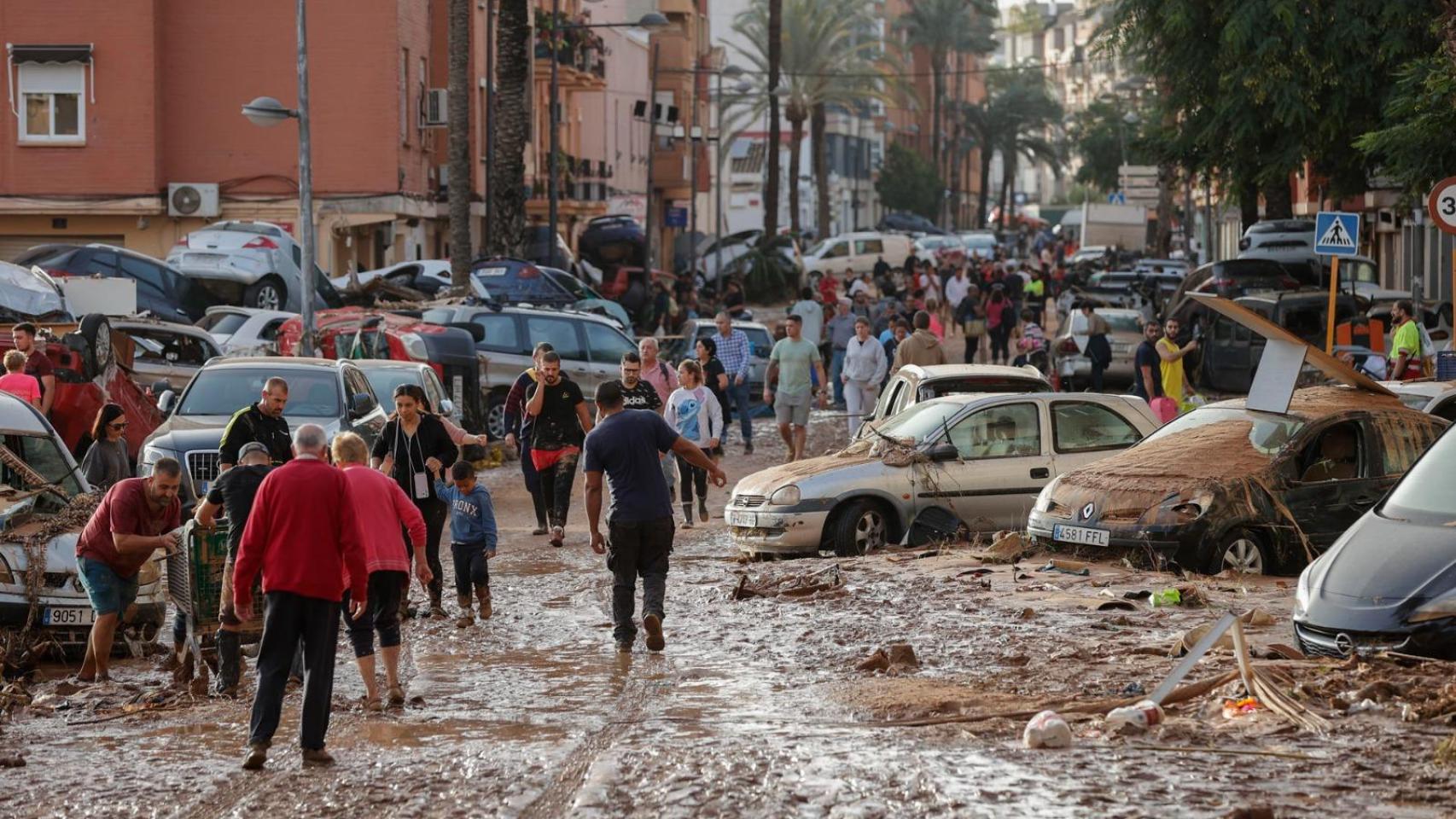 Varias personas caminan entre el lodo acumulado en las calles a causa de las intensas lluvias caídas por la fuerte DANA en Valencia. Efe