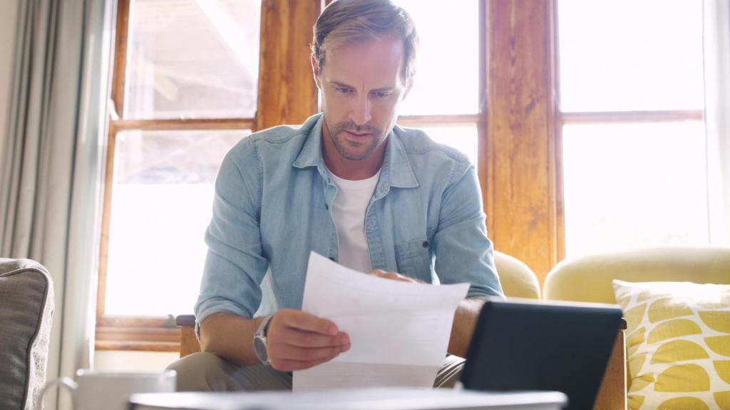 Un hombre revisando un documento asustado, en una imagen de Shutterstock.