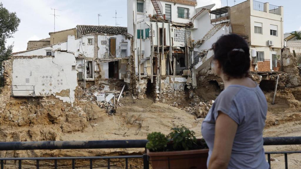 Una mujer observa varias casas dañadas en Chiva.