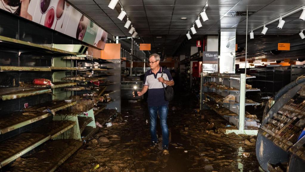 Un hombre busca alimentos en uno de los supermercados de la ciudad, totalmente saqueado y a oscuras.