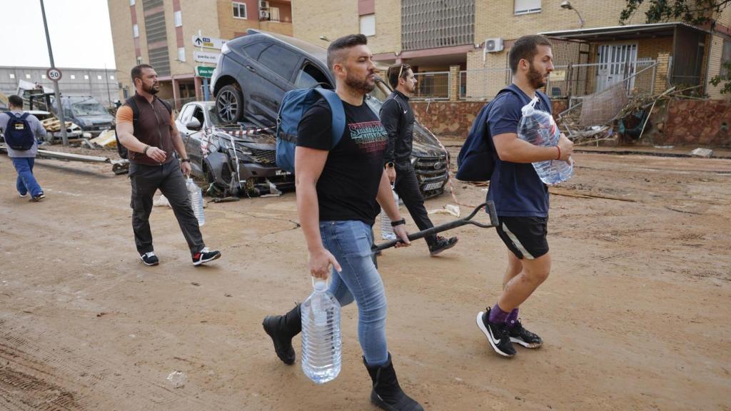 Varios residentes llevan garrafas de agua a la entrada de la localidad de Paiporta.